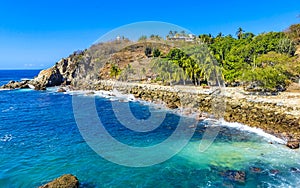 Surfer waves turquoise blue water rocks cliffs boulders Puerto Escondido