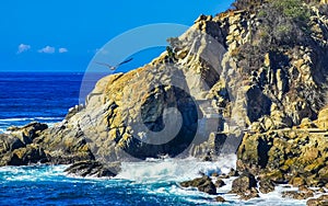 Surfer waves turquoise blue water rocks cliffs boulders Puerto Escondido