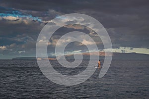 Surfer in wavy pacific ocean on a gloomy day in Maui, Hawaii