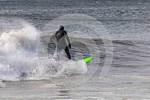 Surfer in a wetsuit carving through ocean waves. Winter cold weather surfing  - Long Island NY