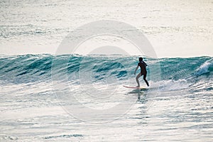 Surfer in wetsuit ride on blue wave. Winter surfing in ocean