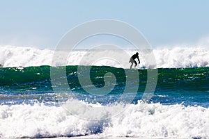 Surfer in wetsuit surfing breaking waves off beach