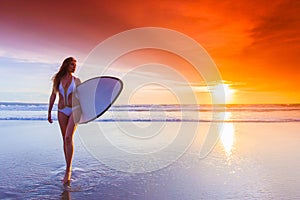 Surfer woman on beach at sunset