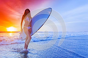 Surfer woman on beach at sunset