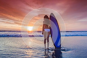 Surfer woman on beach at sunset