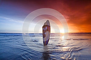 Surfer woman on beach at sunset