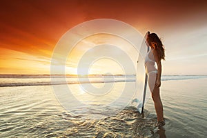 Surfer woman on beach at sunset