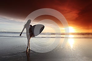 Surfer woman on beach at sunset