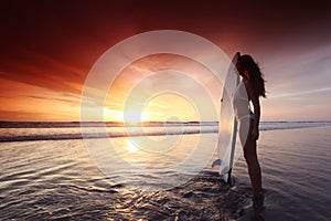 Surfer woman on beach at sunset