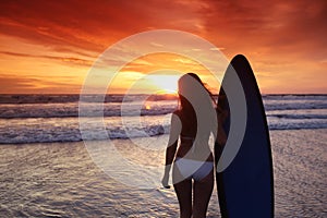 Surfer woman on beach at sunset