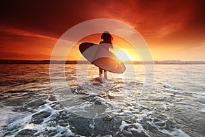 Surfer woman on beach at sunset