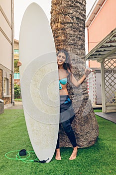 Surfer woman with bikini and wetsuit holding