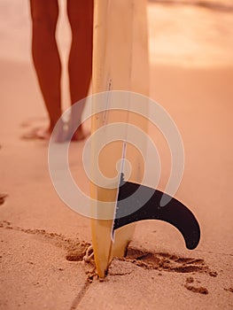 Surfer woman posing with surfboard on the beach at sunset