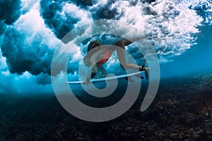 Surfer woman with surf board dive underwater with under big crashing wave