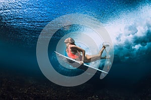 Surfer woman with surfboard dive underwater
