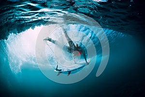 Surfer woman with surfboard dive underwater with under big ocean wave.