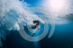 Surfer woman with surfboard dive underwater with under big wave