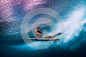 Surfer woman with surfboard dive underwater with under ocean waves
