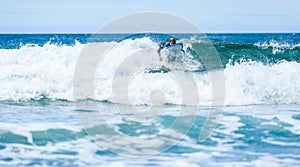 Surfer woman with surfboard is paddling on the wave