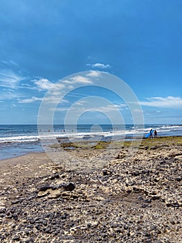 Surfers beach in El Medano on a sunny april day, blue ocean and volcanic rocks coast