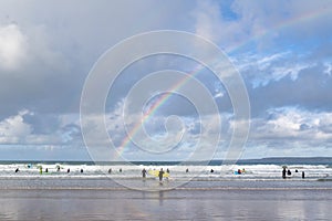 Surfers on the beach in Newquay Cornwall beautiful summer day with a genuine double rainbow over the ocea