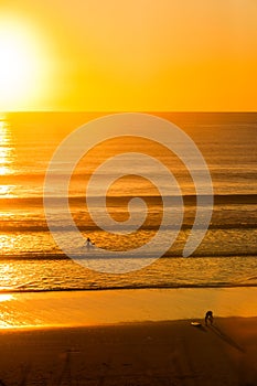 Surfers on beach at sunset