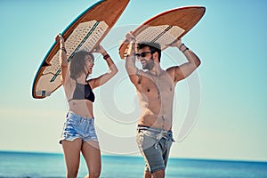 Surfers at the beach- Young couple of surfers walking on the beach and having fun in summer Vacation. Extreme Sport.