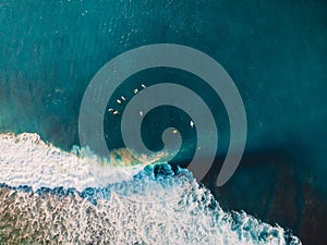 Surfers in blue ocean and barrel wave. Aerial view with drone