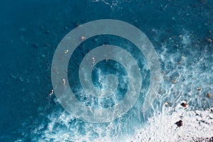 Surfers in blue water seen from above