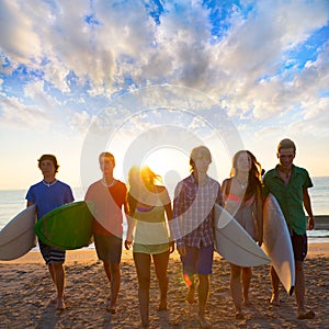 Surfers boys and girls group walking on beach