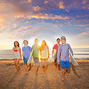 Surfers boys and girls group walking on beach