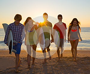 Surfers boys and girls group walking on beach