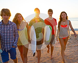 Surfers boys and girls group walking on beach