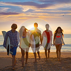 Surfers boys and girls group walking on beach