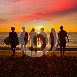 Surfers boys and girls group walking on beach