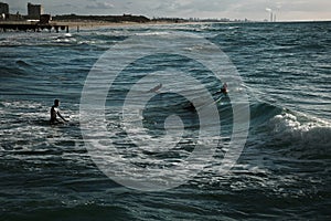 Surfers on the sea wawes at sunset.