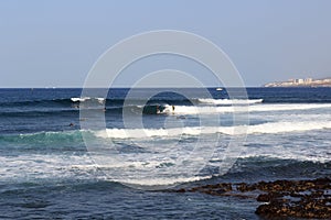 Surfers practising surfing on surfboards and Atlantic Ocean panorama in holiday resort Playa de las Americas on Canary Island