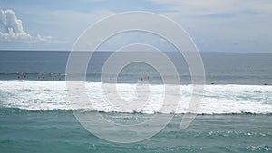 Surfers riding tsunami tidal waves at balinese surfing beach. Bali, Indonesia. 4K
