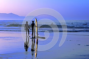 Surfers with sunset reflection on surfboard