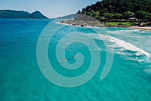 Surfers on surfboard in blue ocean. Aerial view