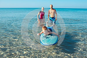 Surfers and their son are going to surf in the ocean in a sunny day