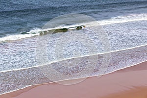 Surfers in the waves off Mawgan Porth Beach, Cornwall, UK