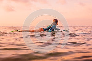 Surfgirl with perfect body on a surfboard floating in ocean