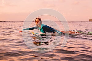 Surfgirl with perfect body on a surfboard floating in ocean