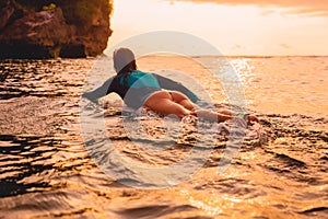 Surfgirl with perfect body on a surfboard floating in ocean.