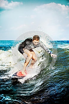 Surfing at blue sea. Young man touched wave on surfboard.