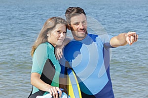 Surfing couple pointing at something