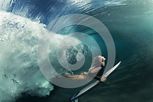 Surfing girl having fun under wave