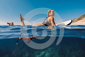 Surfing girl in sexy bikini swimming on surfboard. Active sport lifestyle and summer vacation