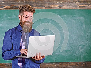 Surfing internet. Teacher bearded man with modern laptop surfing internet chalkboard background. Hipster teacher wear